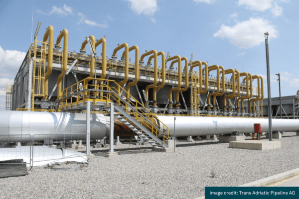 An image of some pipework that performs part of the Trans Adriatic Pipeline in Southern Europe. The pipe work is silver and yellow, and also features a set of steps up to the pipework facility